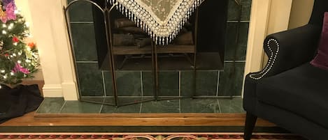 A living room with a fireplace, a Christmas tree, and a decorative bowl with flowers.