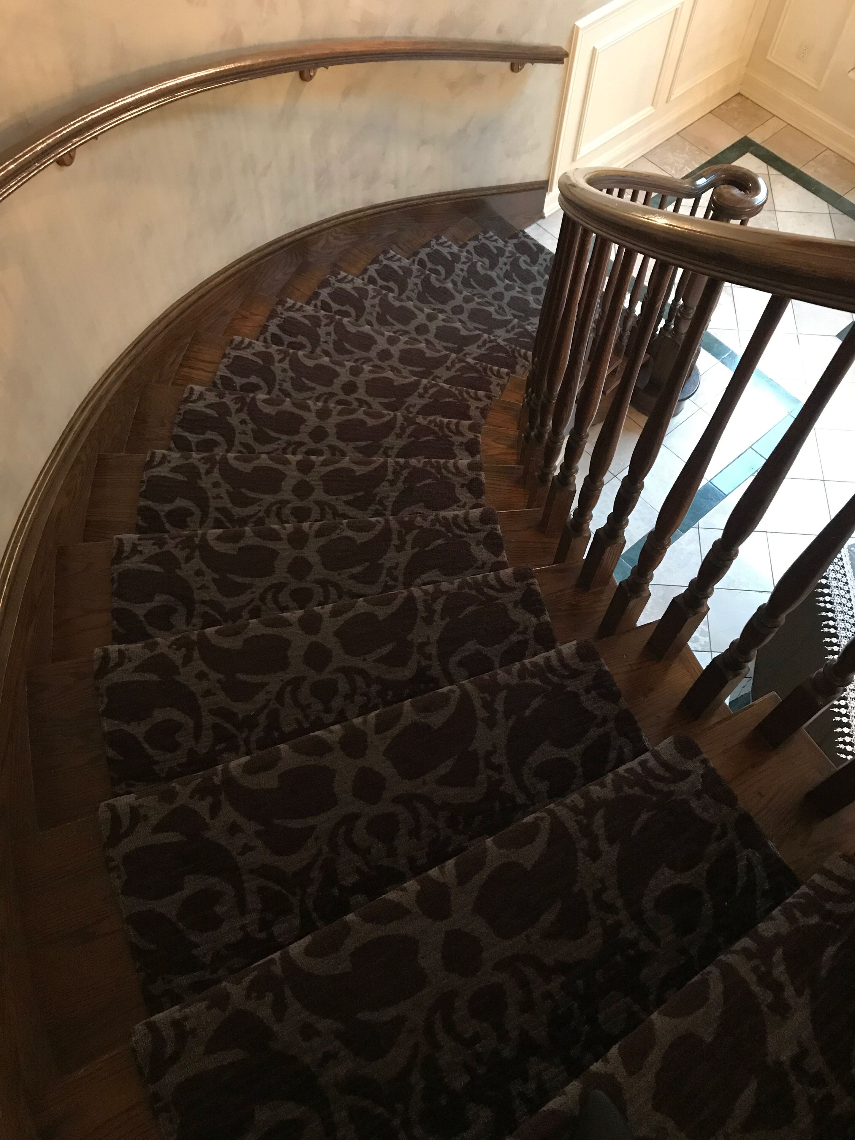 A spiral staircase with a leopard print carpet and wooden balusters.