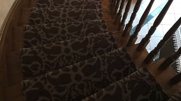 Una escalera de caracol con alfombra de estampado de leopardo y barandilla de madera.