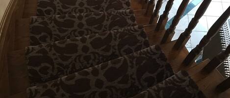 A spiral staircase with a leopard print carpet and wooden balusters.