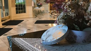 A lobby with a chandelier, a gift shop sign, and a large floral arrangement. - Hotel Grand Victorian (Branson)