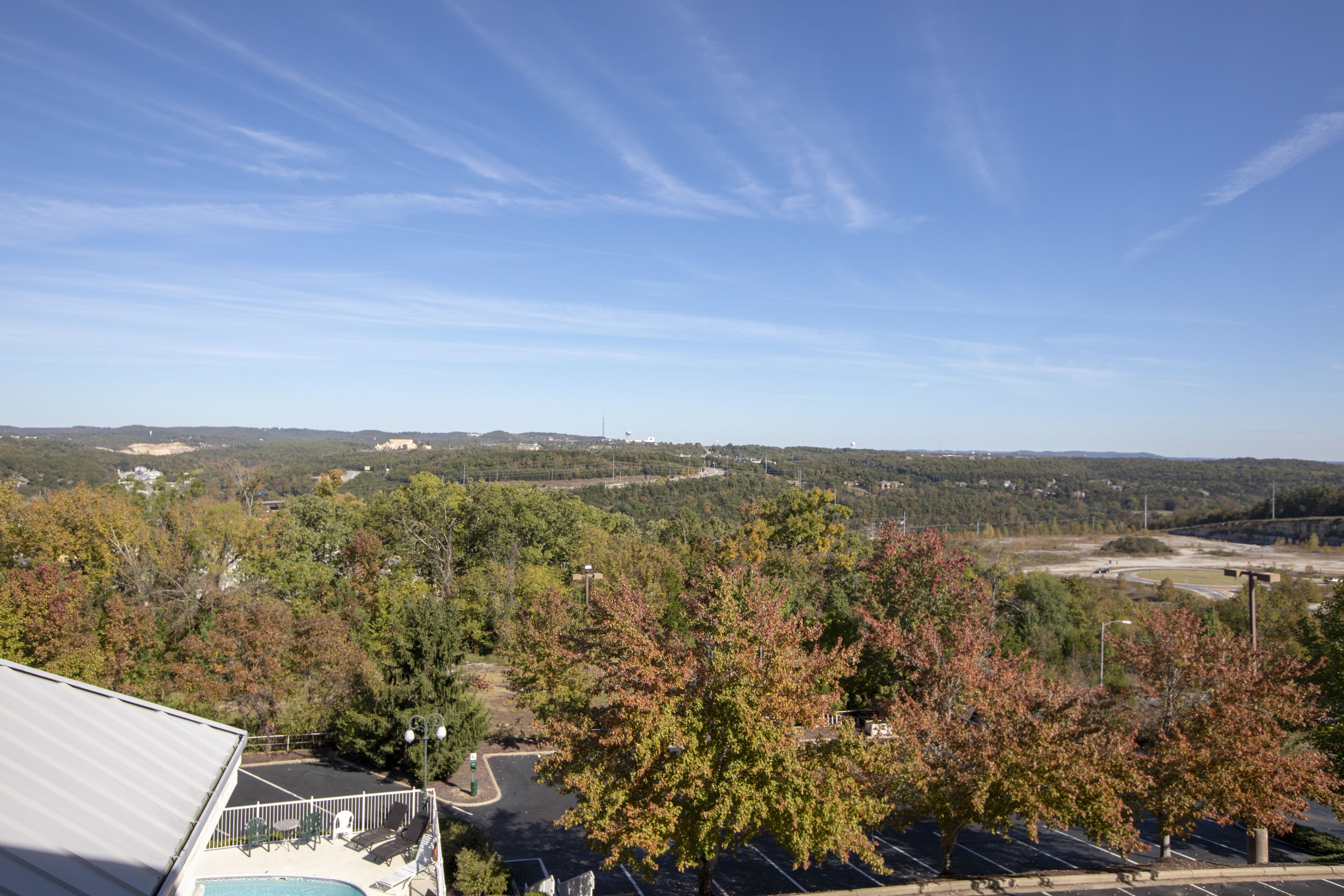 A view of a parking lot with trees and a building in the foreground.