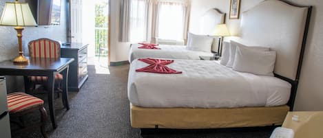 A hotel room with two beds, a desk, a chair, a TV, and a bathroom.