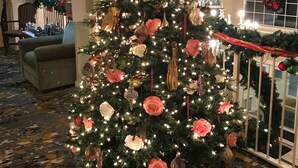 A Christmas tree with ornaments and lights, surrounded by wrapped gifts. - Hotel Grand Victorian (Branson)