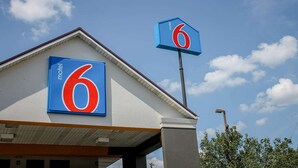 Un motel con un llamativo letrero con el número '6' en el edificio y otro letrero similar en un poste.