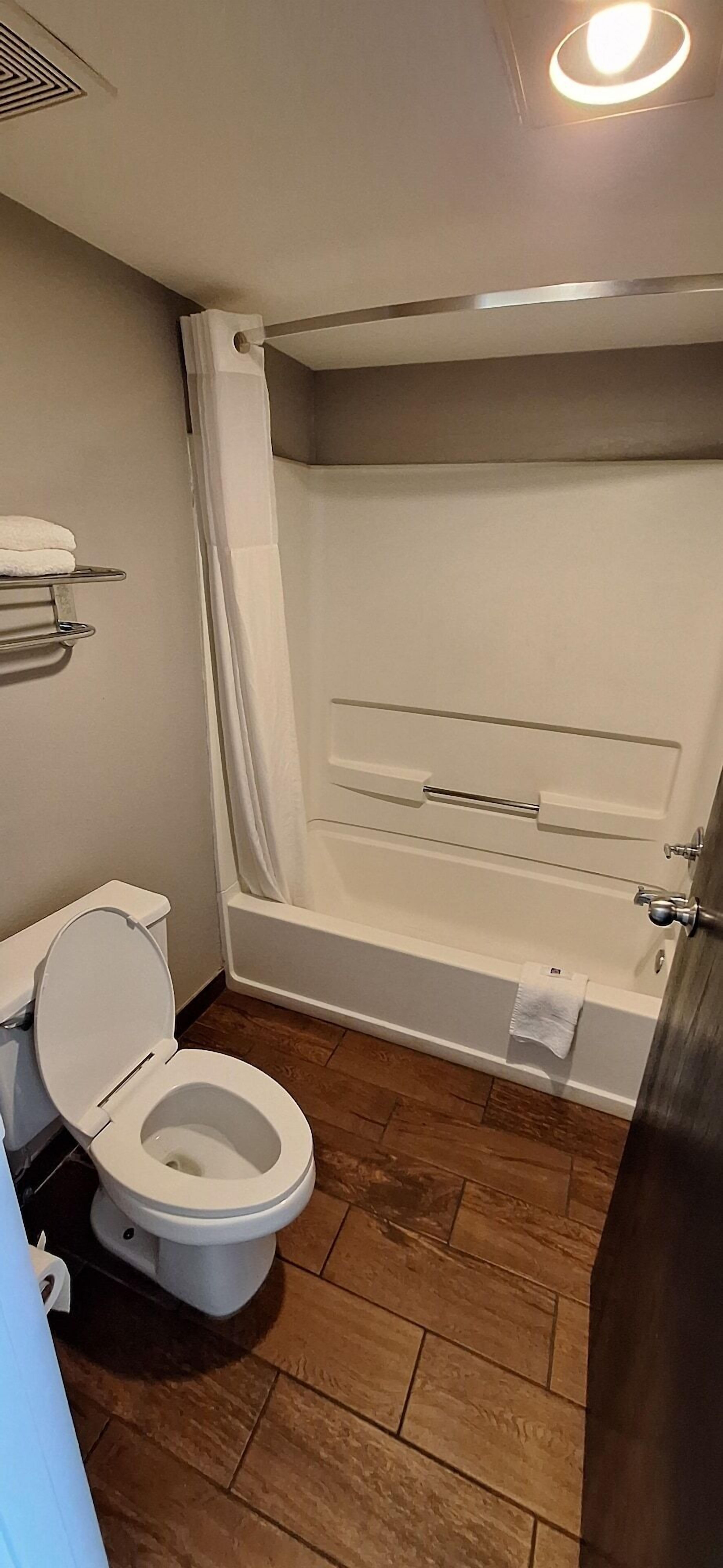 Une salle de bain équipée de toilettes, d’une baignoire et d’un rideau de douche.