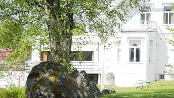 A white building with a large tree in front.