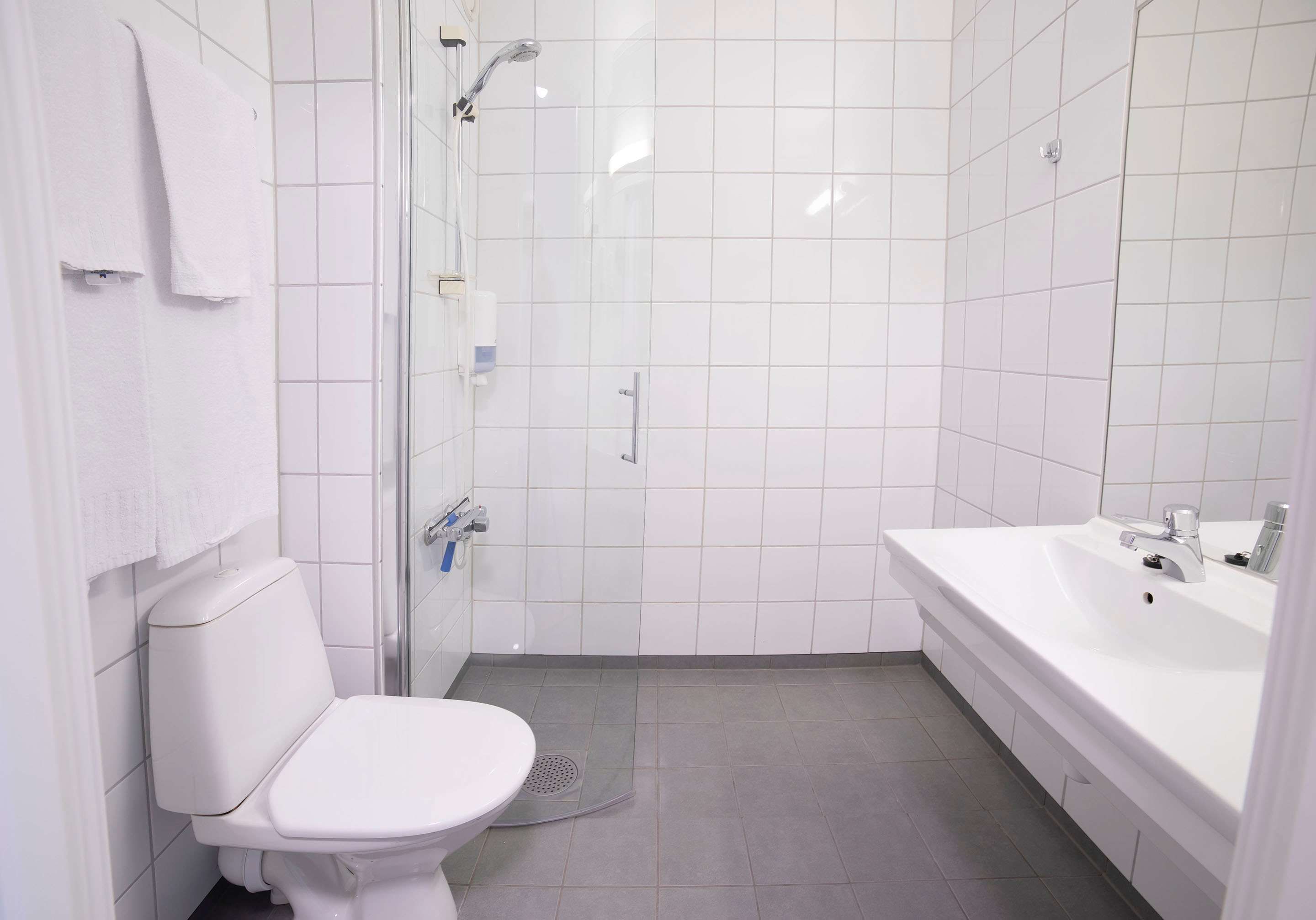 A modern bathroom with a toilet, shower, and sink.