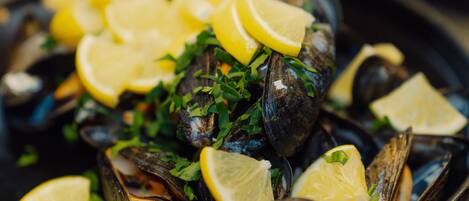 Primer plano de mejillones adornados con rodajas de limón y perejil picado.