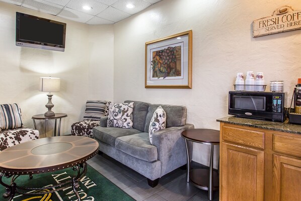 Relax in this cozy living space with a comfortable sofa, wall-mounted TV, and kitchenette featuring a microwave, coffee machine, and refrigerator.