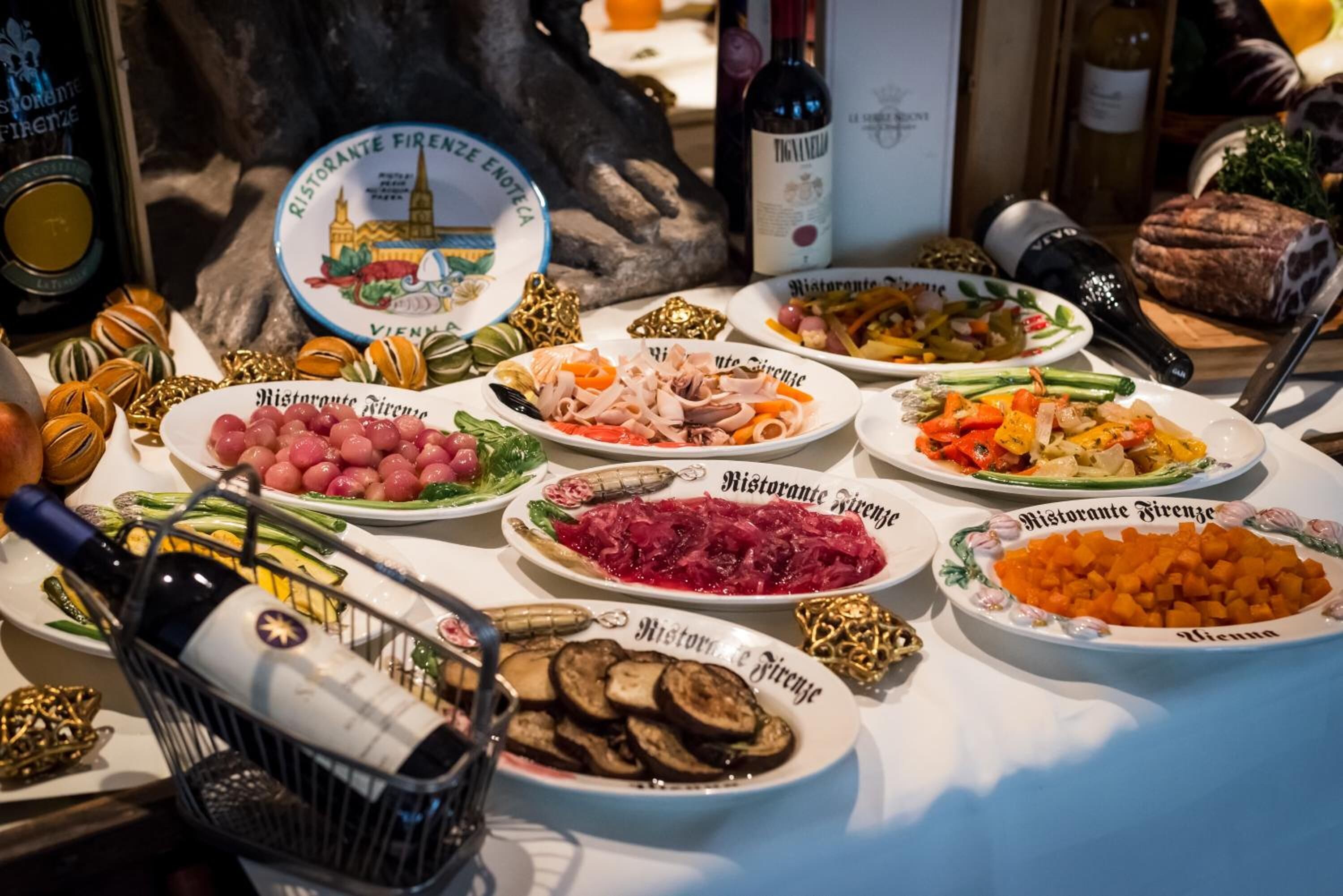 Uma mesa com vários pratos e garrafas de vinho, sugerindo um ambiente de refeições.
