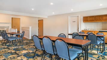 Une chambre d’hôtel avec un coin repas, une cuisine et une moquette à motifs.