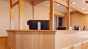 Un comptoir d’accueil avec un revêtement en bois, un espace détente avec des sièges noirs rembourrés et un sol carrelé.