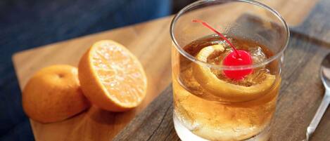 A glass of iced beverage with a cherry on a wooden table.