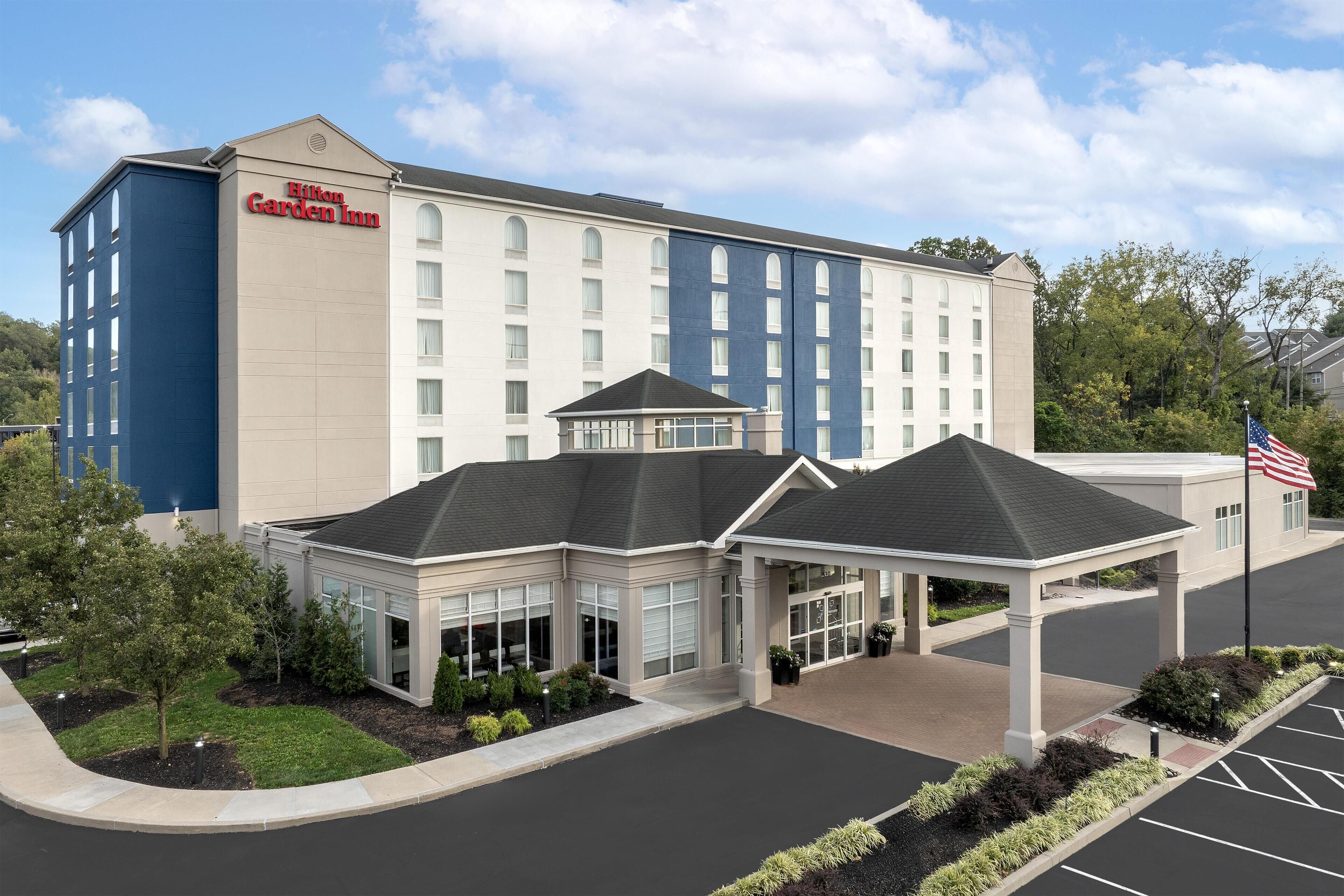 Un Hilton Garden Inn con facciata moderna, ingresso coperto e parcheggio.