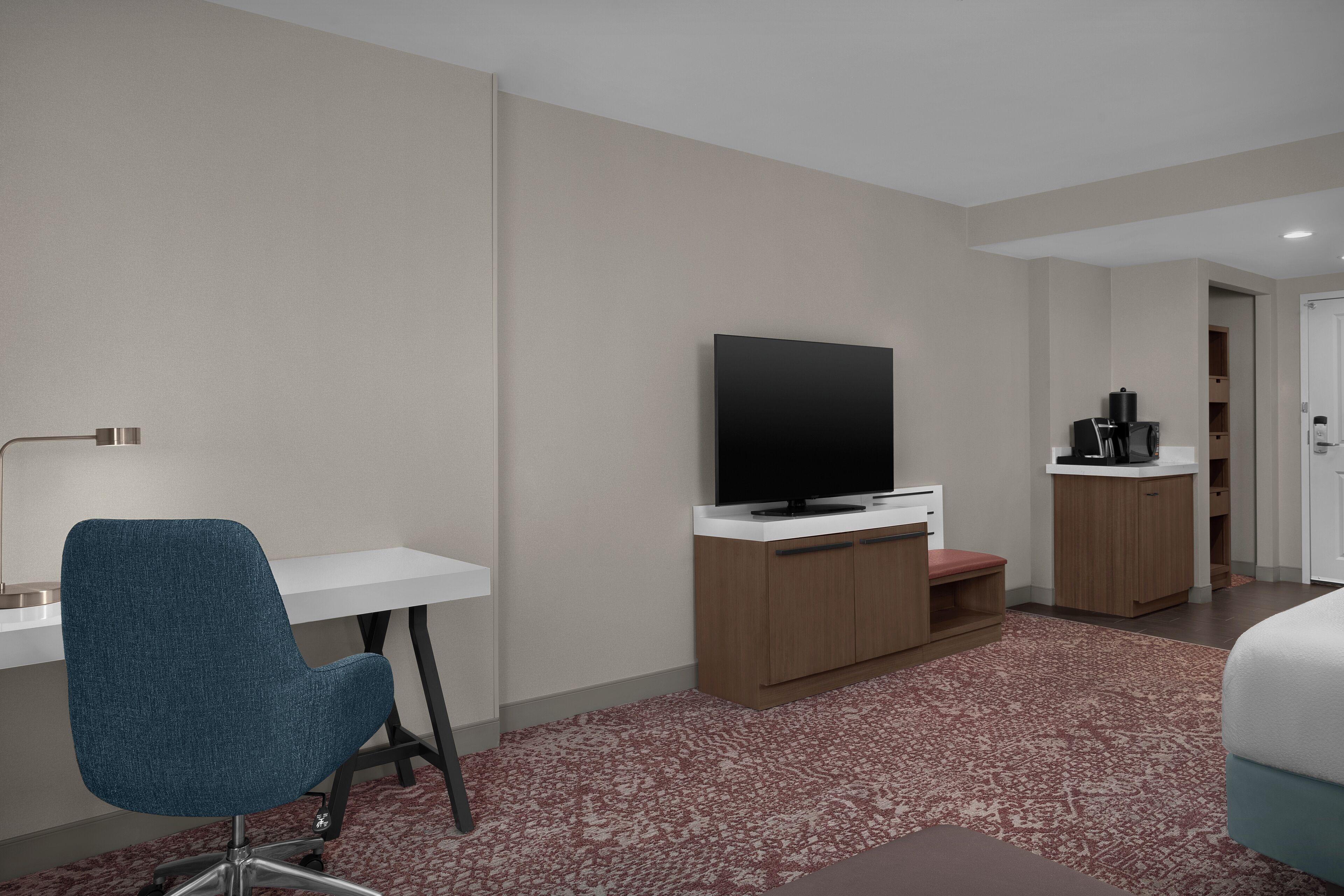 Une chambre d’hôtel équipée d’un bureau, d’une chaise, d’une télévision et d’un lit.