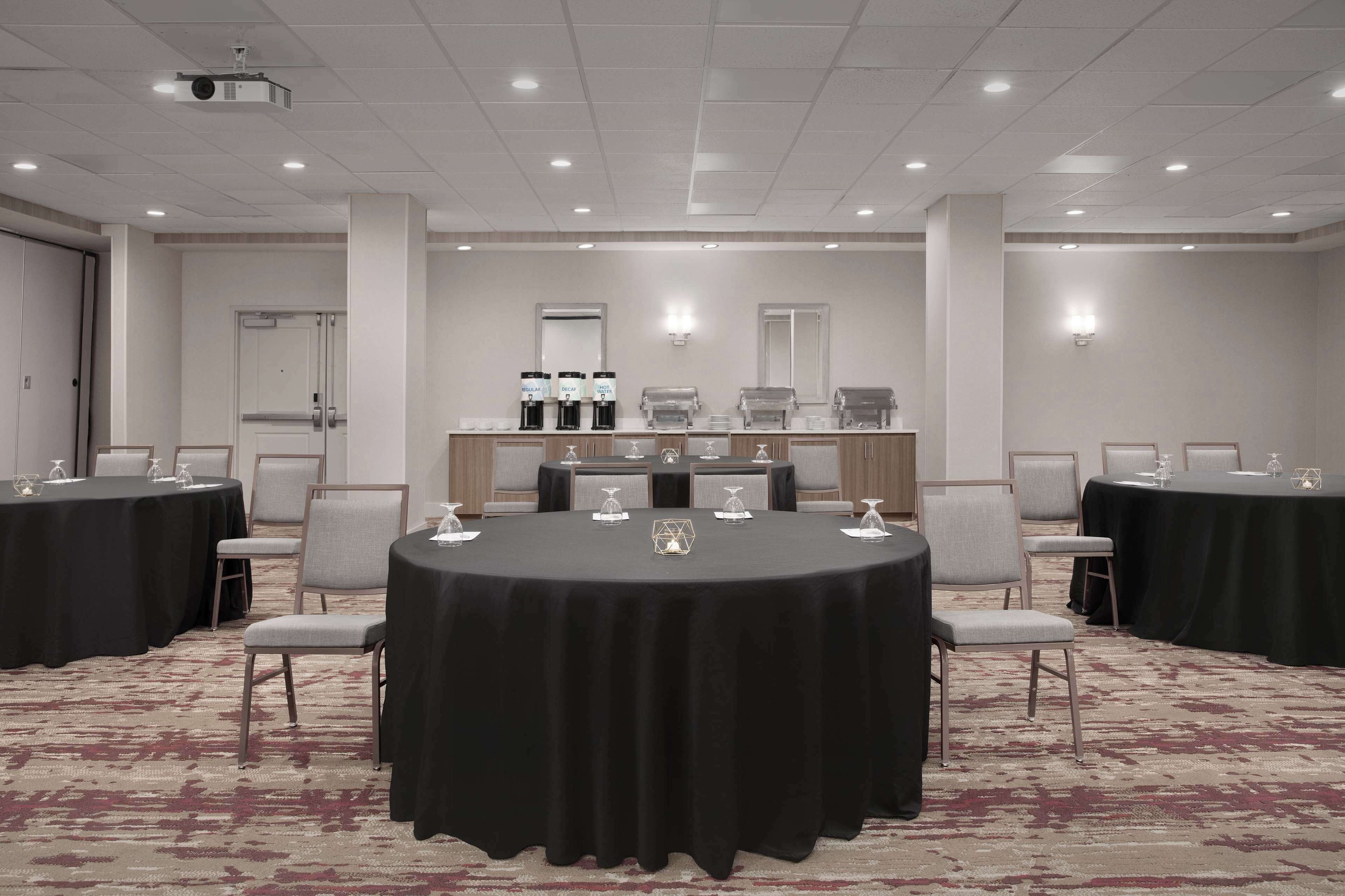 A conference room with round tables, chairs, and a coffee station.