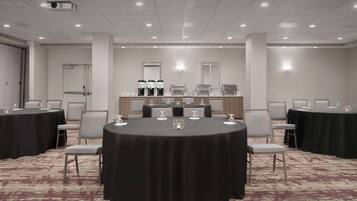 A conference room with round tables, chairs, and a coffee station.