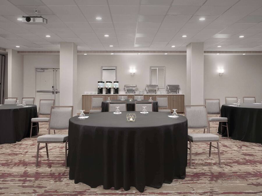 A conference room with round tables, chairs, and a coffee station.