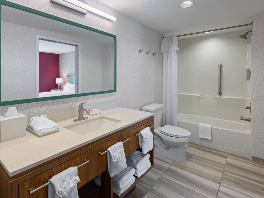 Un baño moderno con un espejo grande, un lavabo, un inodoro y una zona de ducha.