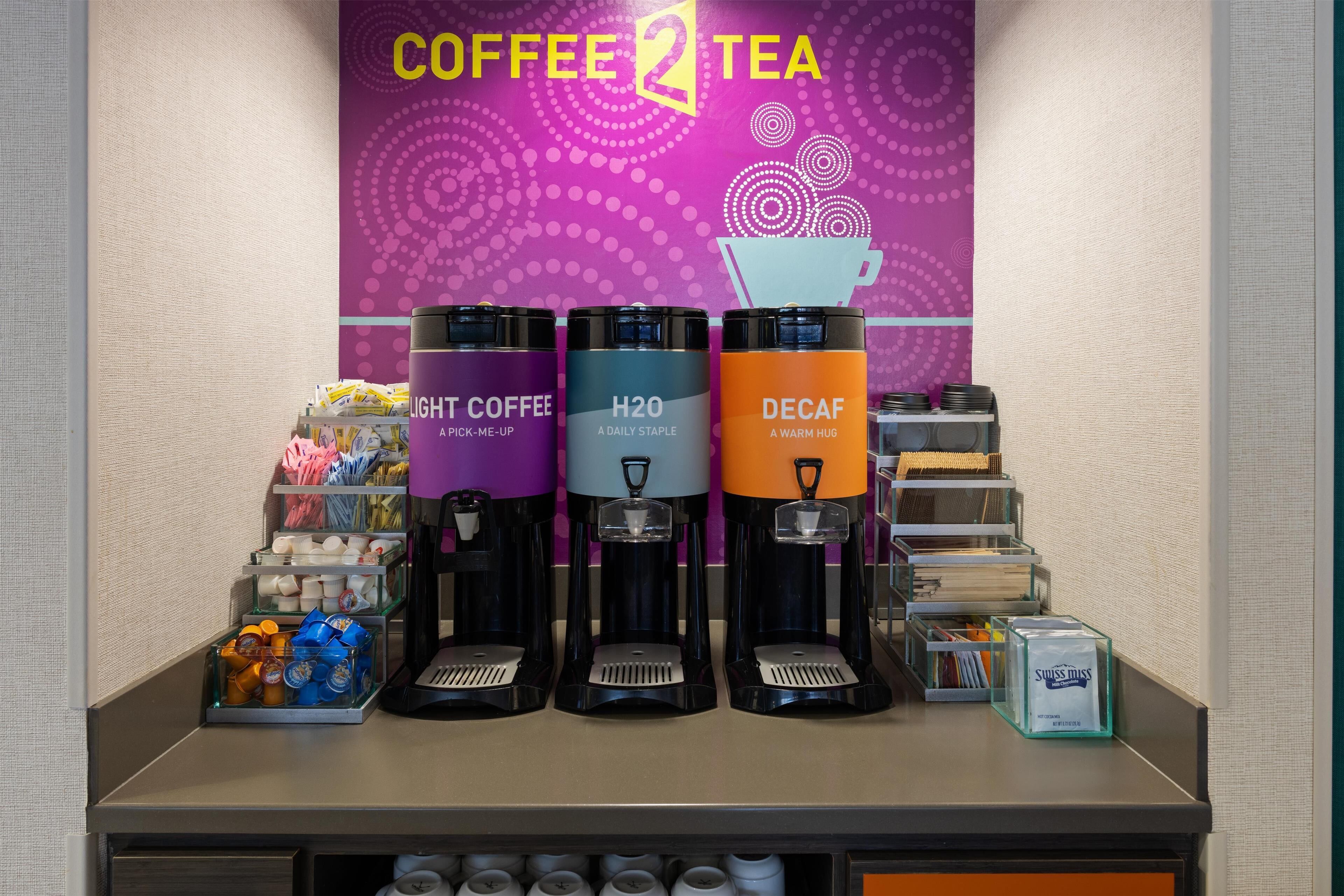 Un espace dédié au café et au thé, équipé de trois distributeurs étiquetés « CAFÉ LÉGER », « H2O » et « CAFÉ DÉCAFÉINÉ ».