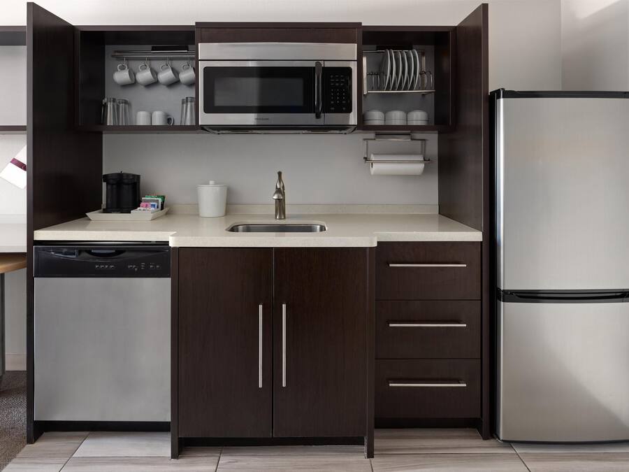 A modern kitchen with dark wood cabinets, stainless steel appliances, and a dishwasher.