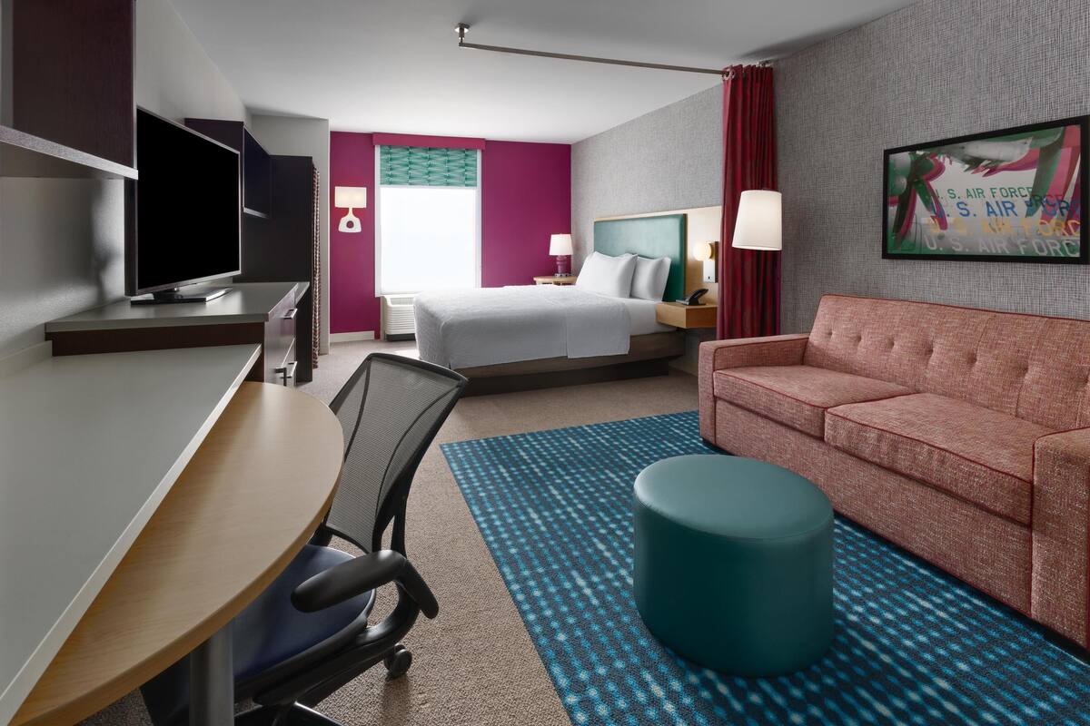 A hotel room with a bed, a desk with a computer, a couch, and a television.
