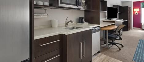 A modern kitchen with a built-in microwave, stainless steel sink, and dark wooden cabinets.