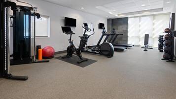 A gym with cardio machines, weightlifting equipment, and exercise balls.