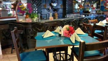 A restaurant with wooden tables and chairs, blue tablecloths, and decorative flowers.