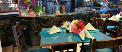 A restaurant with wooden tables and chairs, blue tablecloths, and decorative flowers.