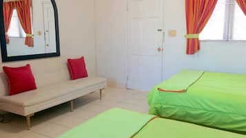 Un dormitorio con un sofá blanco, dos camas verdes, una puerta blanca y un espejo con cortinas.