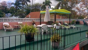 Een terras op het dak met buitenmeubilair, plantenbakken en een overdekt gedeelte met parasols.