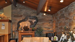 A lobby with a stone wall, a fireplace, a sofa, and a deer wall art piece.