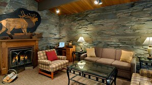 A cozy living room with a stone wall, a fireplace, a sofa, a chair, and a coffee table.