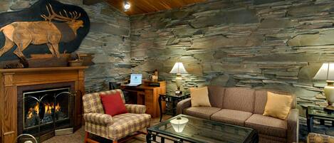 A cozy living room with a stone wall, a fireplace, a sofa, a chair, and a coffee table.