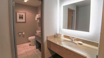 A bathroom with a sink, mirror, toilet, and towel rack.