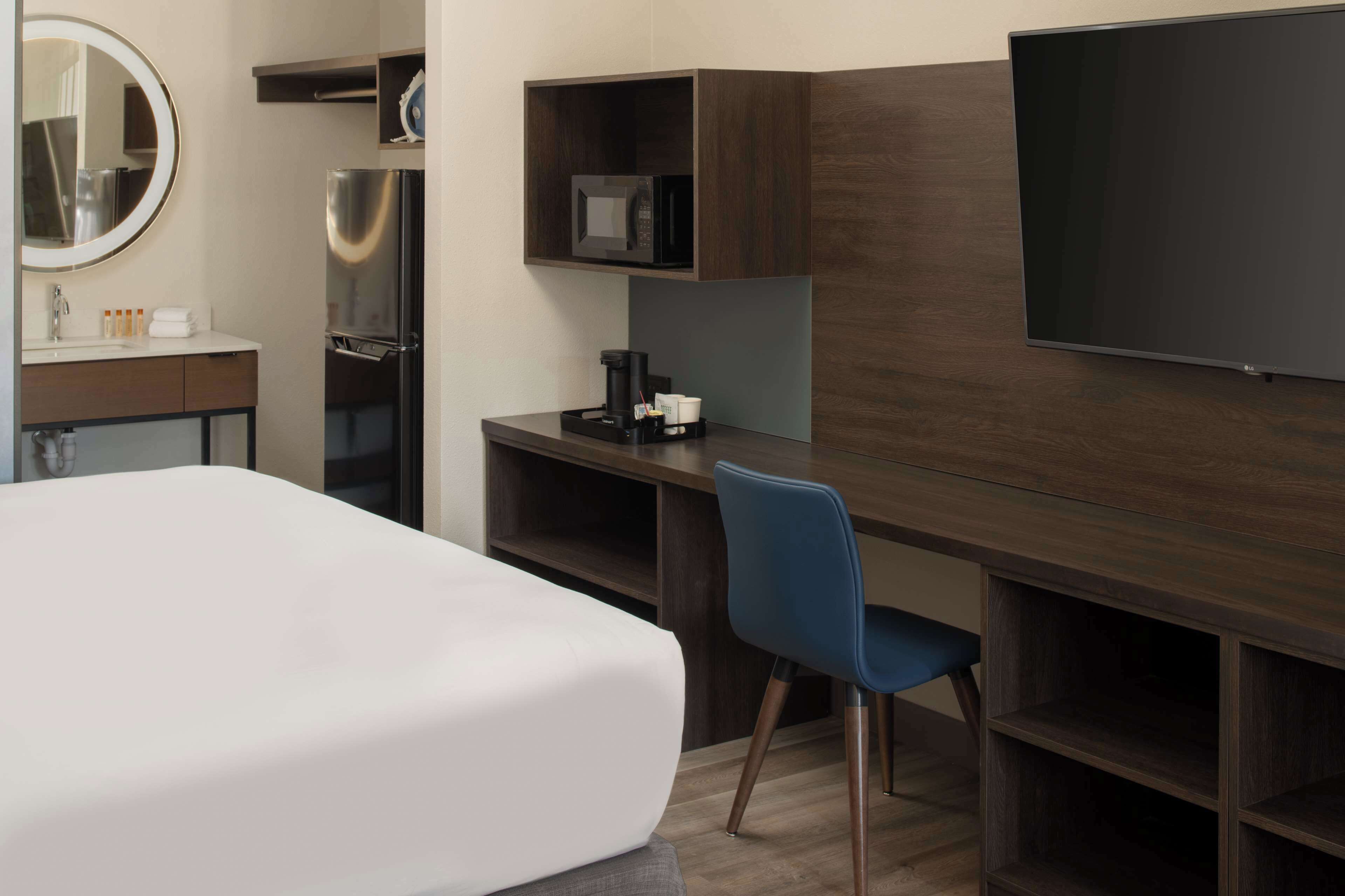 A hotel room with a large bed, a desk with a computer, a TV, and a microwave.