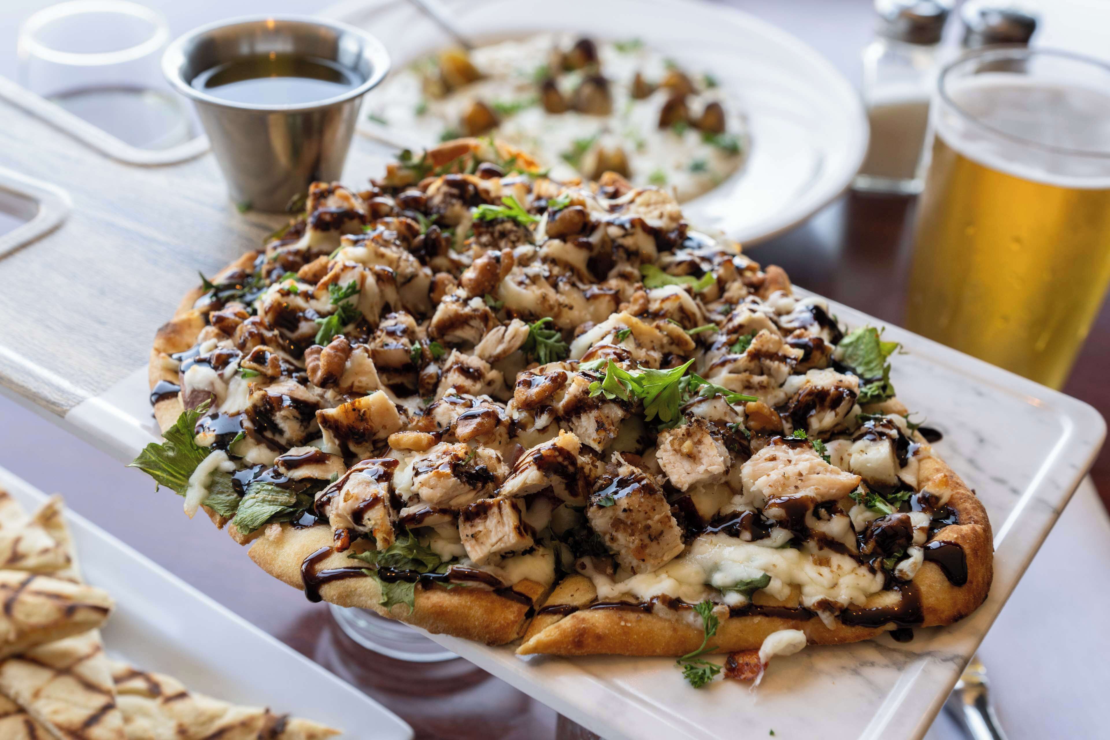 A pizza with various toppings and sauces on a white plate.