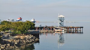 A waterfront area with a dock, a small tower, and a park with trees.