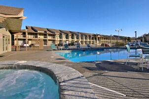 Un motel con piscina, sillas de descanso y bañera de hidromasaje.