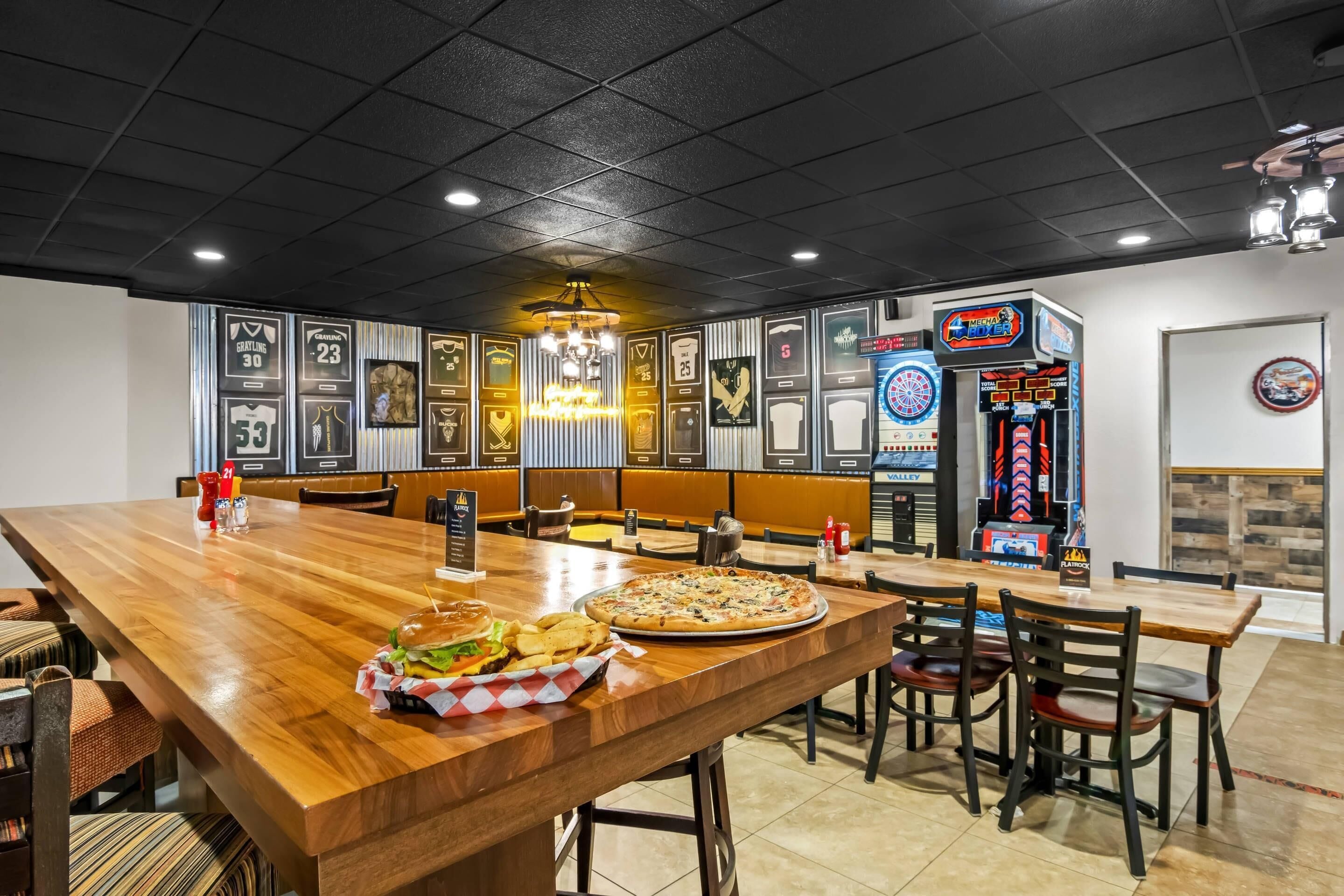 A restaurant with a long wooden table, pizza, and a basket of fries.