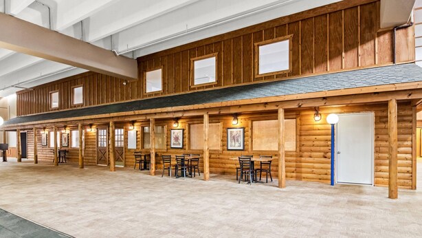 A long, wooden building with multiple windows and doors, featuring a tiled floor and several tables and chairs. - Quality Inn & Suites (Grayling)