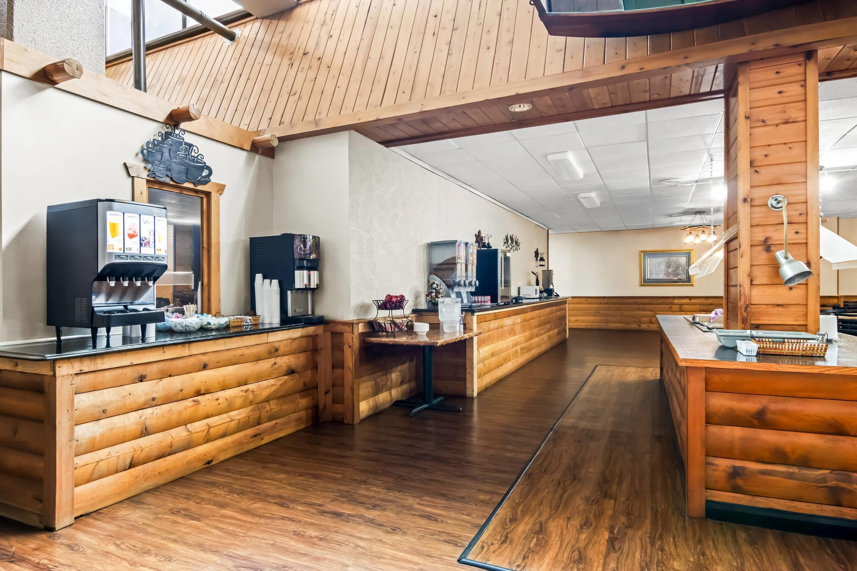 Een houten interieur met een koffieapparaat, een tafeltje en een aanrecht.