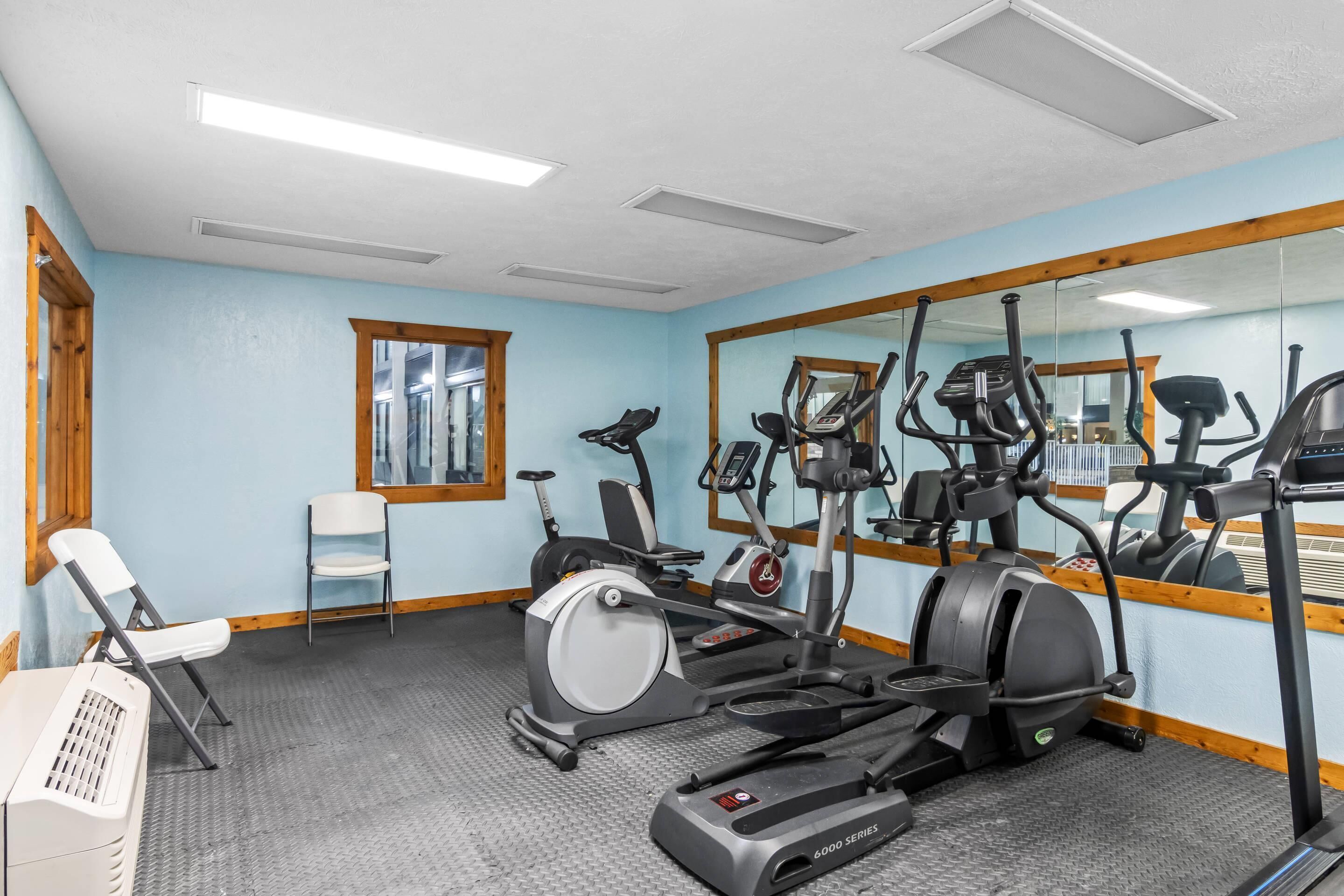 A gym with exercise equipment, a mirror, and a window.