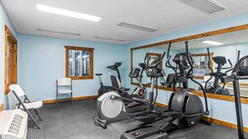 Uma academia com equipamentos de exercícios, um espelho e uma janela.