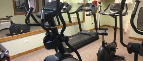 A gym with stationary bikes, treadmills, and a mirrored wall.