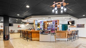 A bar area with multiple seating options, a counter with a display case, and a variety of bottles on shelves. - Quality Inn & Suites (Grayling)