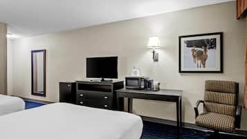 A hotel room with two beds, a desk with a TV, a microwave, a chair, and a framed picture on the wall.
