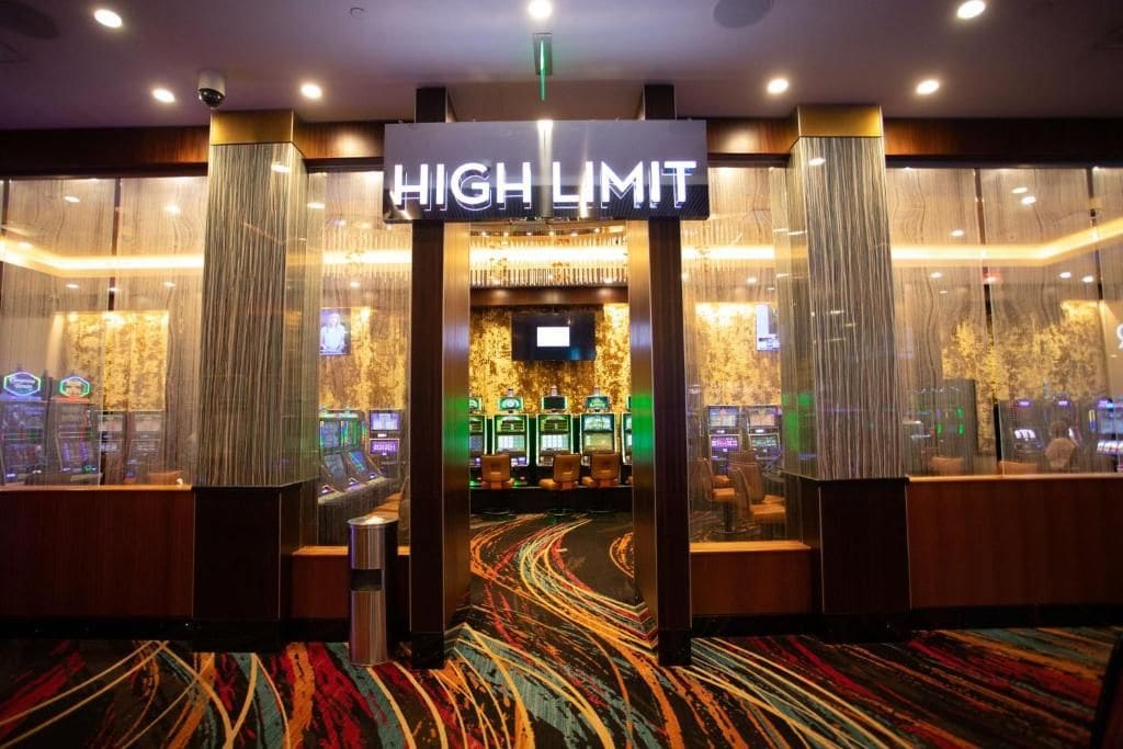 Entrada a un casino con un letrero que dice 'HIGH LIMIT', máquinas tragamonedas y piso alfombrado.